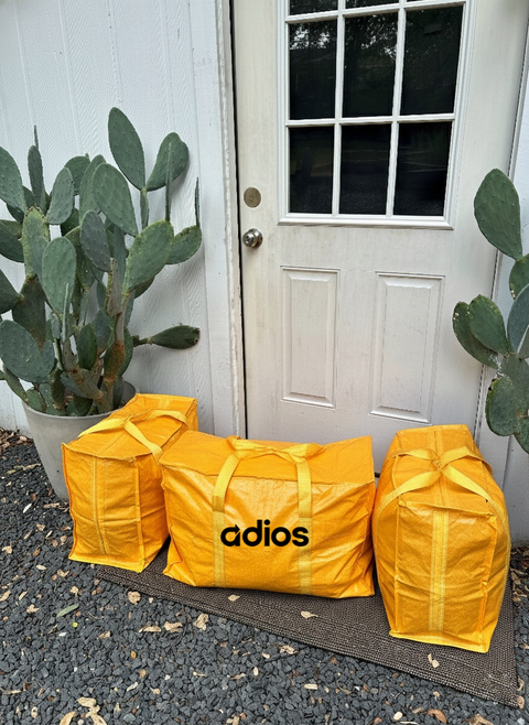 Three yellow bags with 'adios' branding in front of a white door.