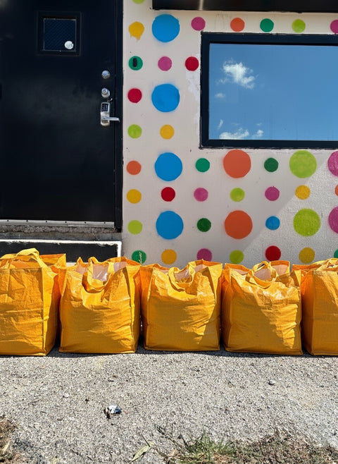 Yellow bags lined up against a colorful polka dot wall.