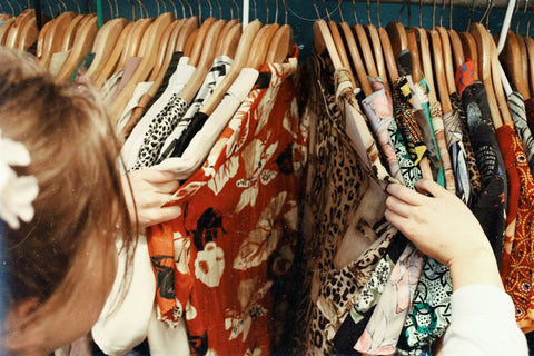 Person browsing through a rack of patterned clothing in a store.