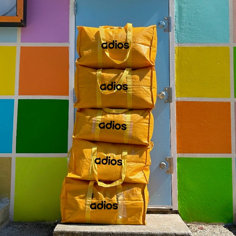 Five yellow Adios goodbye bags stacked in Austin for decluttering and reuse